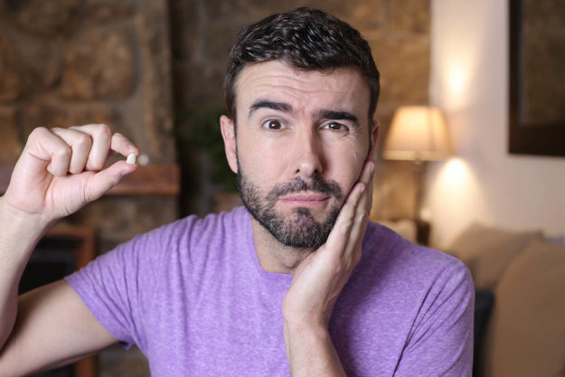 a man rubbing his cheek and holding a tooth because his tooth got knocked out