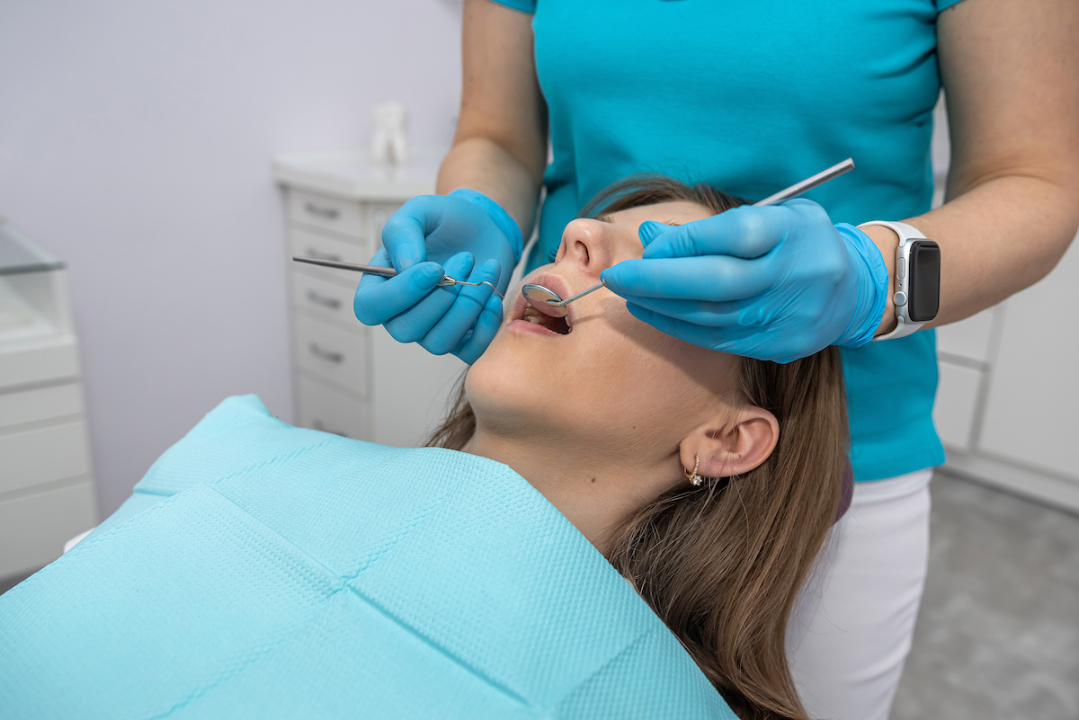 A woman dentist and her assistant in examine the teeth of a woman who came to the reception. woman in dental chair learning about causes of loose teeth roots
