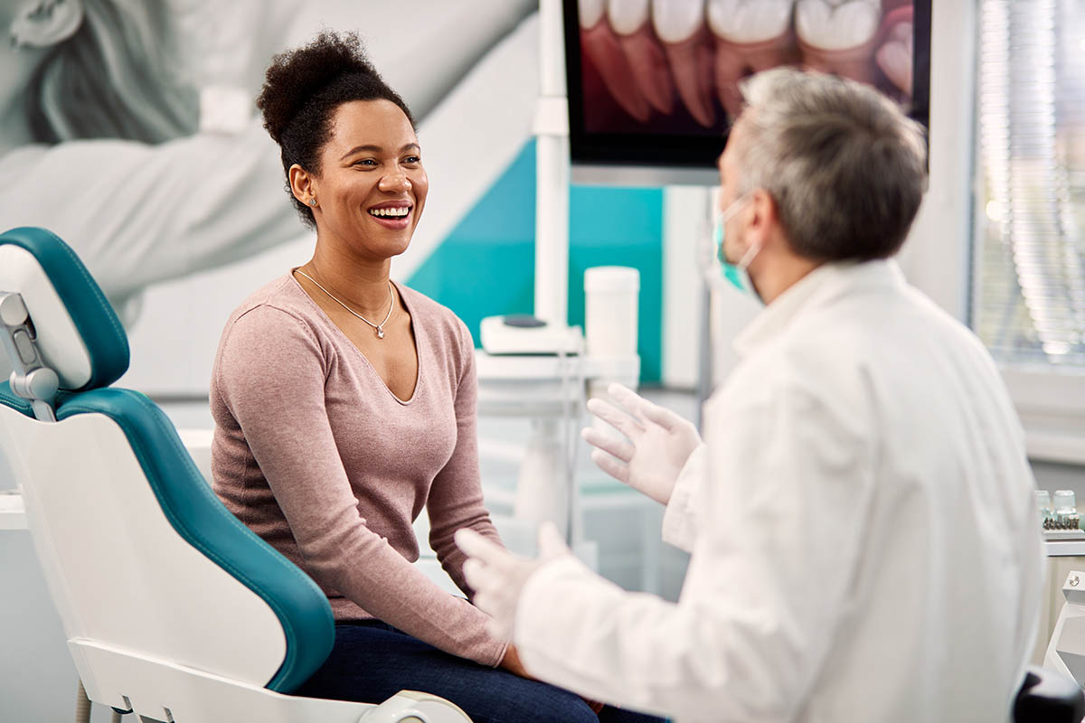 woman in pink sweater talking to endodontist about what to expect in endodontic retreatment