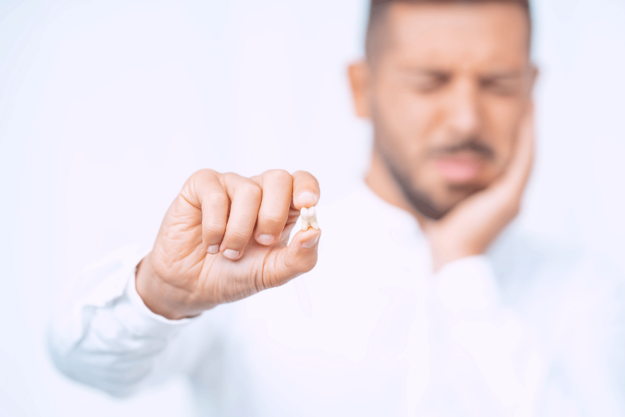 a man holds up his knocked out tooth