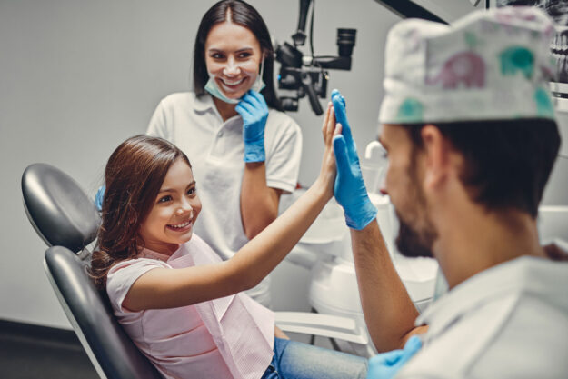 a dentist high fives a pediatric patient after a root canal