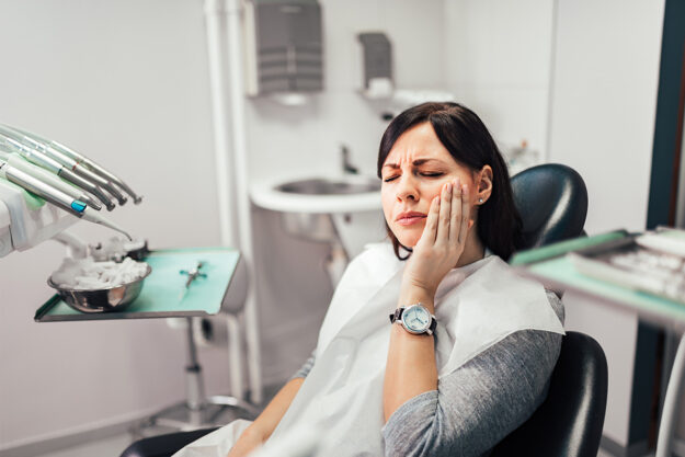 a dental patient in pain waits for her root canal retreatment to start
