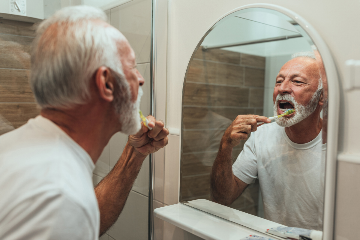 Senior looking in mirror and brushing teeth