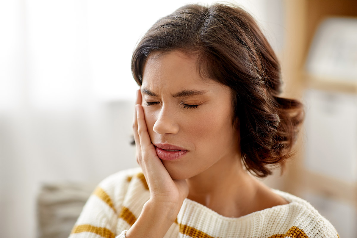 Woman holding her mouth in tooth pain from a cracked crown